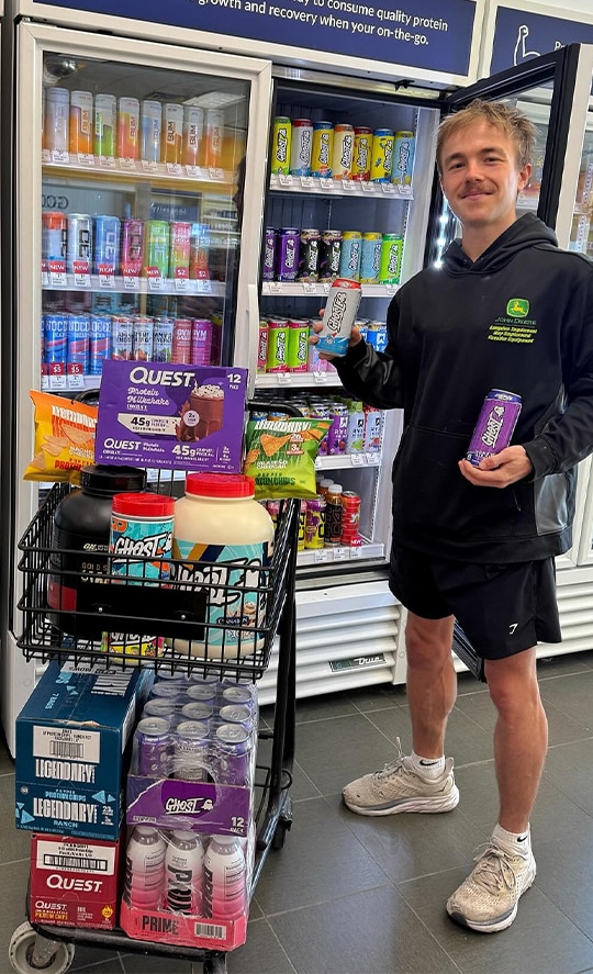 A man showing GHOST drinks in Vitamin Shoppe store